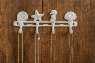 Decorative wall hook with seashell, starfish, and seahorse designs on a wooden background.