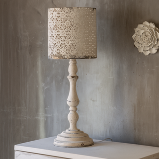 Decorative table lamp with textured shade on a wooden surface against a gray wall.