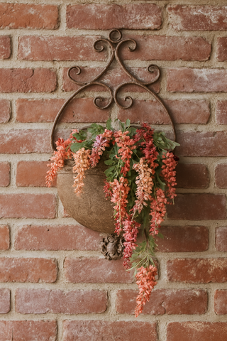 Decorative wall planter with flowers against a brick wall